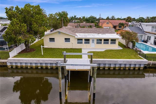 exterior space with a water view, a residential view, fence, and a lawn