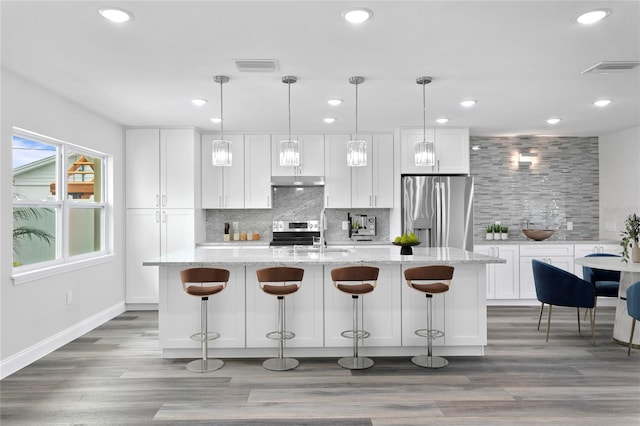 kitchen featuring white cabinetry, an island with sink, stainless steel appliances, and hardwood / wood-style flooring