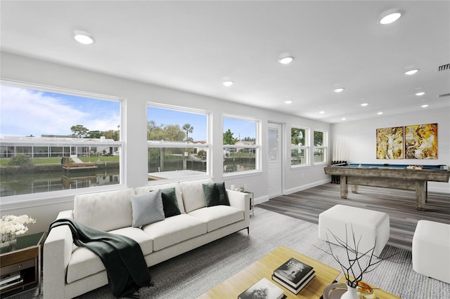 living room with plenty of natural light, a water view, wood-type flooring, and billiards