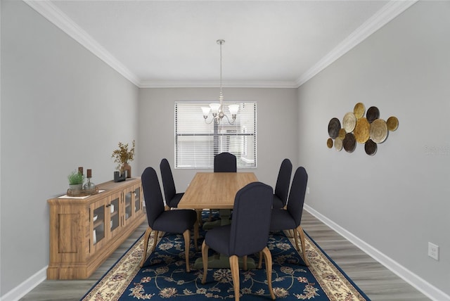 dining area featuring a chandelier, crown molding, baseboards, and wood finished floors