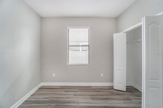 unfurnished bedroom featuring a closet, wood finished floors, and baseboards