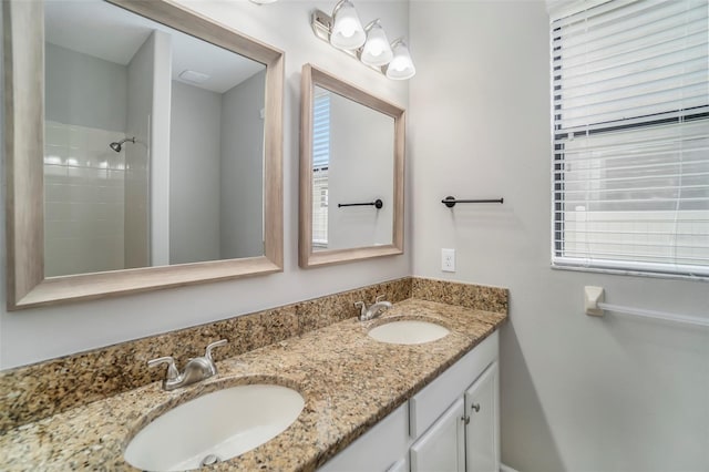 bathroom featuring double vanity, a shower, and a sink