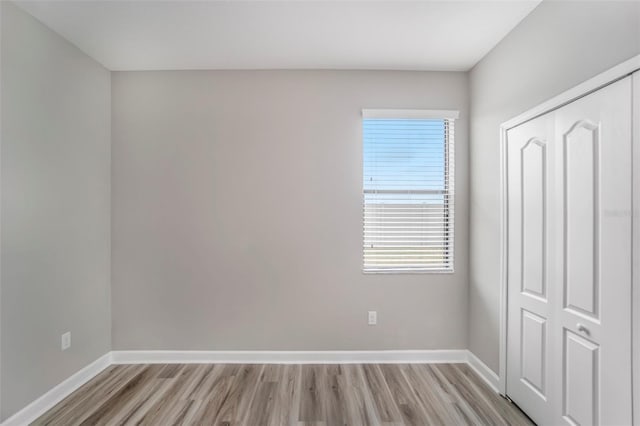 unfurnished bedroom featuring a closet, light wood-type flooring, and baseboards