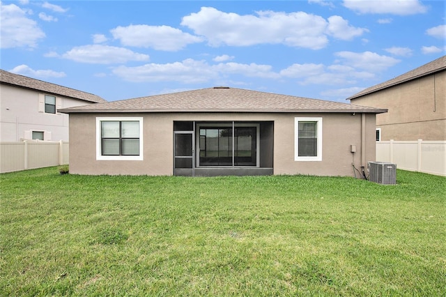 rear view of house with roof with shingles, stucco siding, a lawn, cooling unit, and a fenced backyard