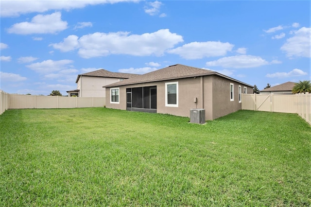 back of house featuring a fenced backyard, central AC, a sunroom, a lawn, and stucco siding