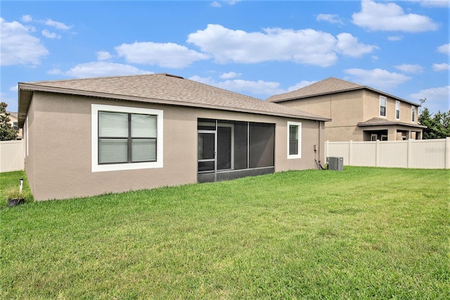 back of house with a fenced backyard, a shingled roof, a sunroom, a lawn, and stucco siding