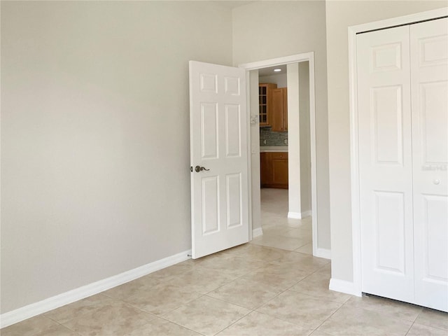 interior space featuring a closet, baseboards, and light tile patterned floors