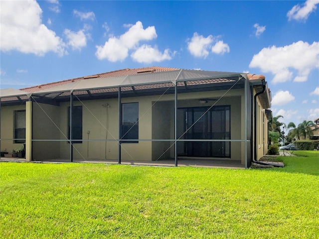 back of property with a yard, a tile roof, a lanai, and stucco siding