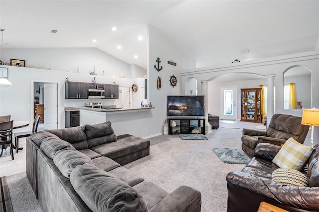 living room with high vaulted ceiling, decorative columns, and light colored carpet