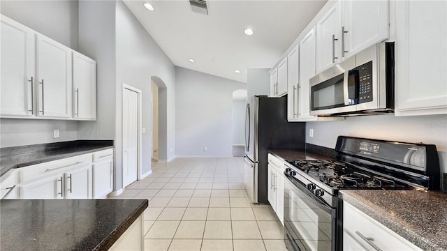 kitchen featuring vaulted ceiling, white cabinets, stainless steel appliances, and light tile patterned floors