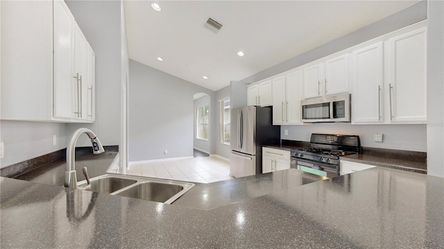 kitchen featuring white cabinetry, sink, stainless steel appliances, vaulted ceiling, and light tile patterned flooring