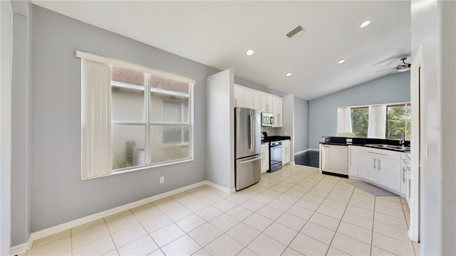 kitchen with sink, vaulted ceiling, light tile patterned floors, appliances with stainless steel finishes, and white cabinetry