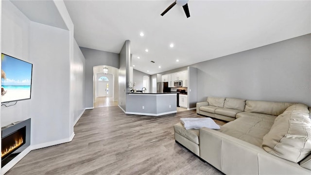 living room with ceiling fan, sink, and light hardwood / wood-style floors