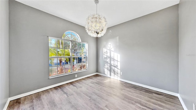 spare room featuring a chandelier and wood-type flooring