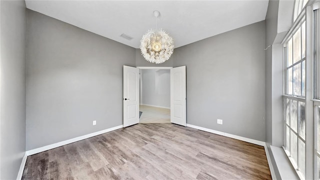 unfurnished room featuring light hardwood / wood-style floors and a notable chandelier