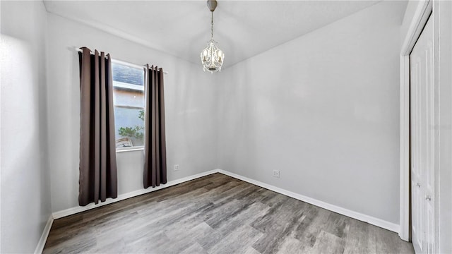 empty room featuring a chandelier and hardwood / wood-style floors