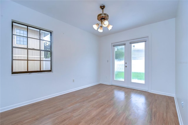 unfurnished room with baseboards, wood finished floors, and french doors