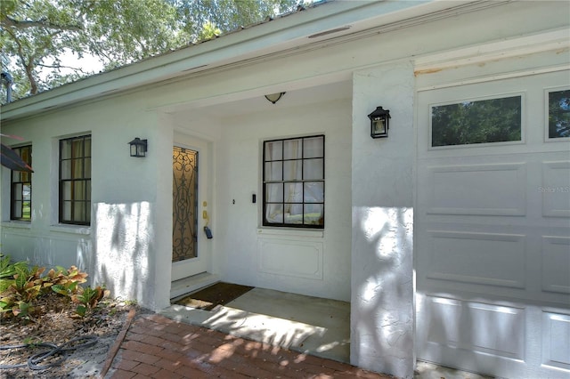 entrance to property with a garage and stucco siding