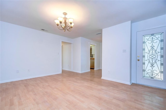 entryway featuring a chandelier, light wood-type flooring, visible vents, and baseboards