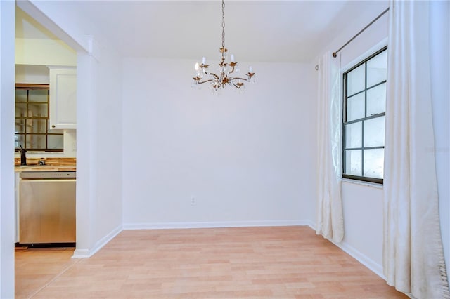 unfurnished dining area with baseboards, a notable chandelier, and light wood finished floors