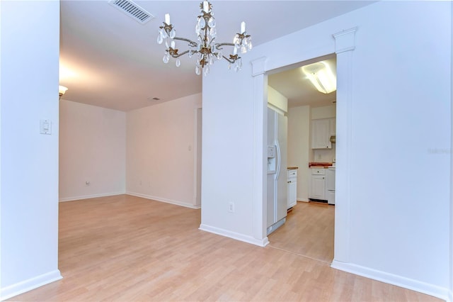 interior space with a chandelier, light wood-type flooring, visible vents, and baseboards