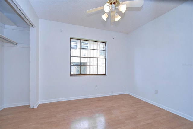 spare room with light wood finished floors, a ceiling fan, and baseboards