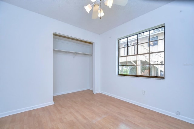 unfurnished bedroom featuring baseboards, a ceiling fan, wood finished floors, a textured ceiling, and a closet