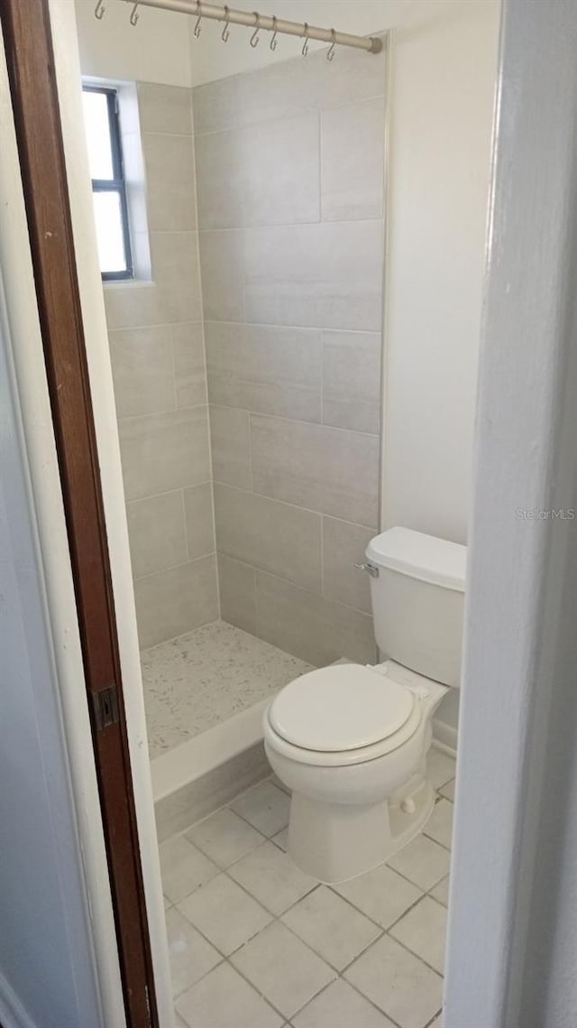 bathroom featuring toilet, a shower stall, and tile patterned floors