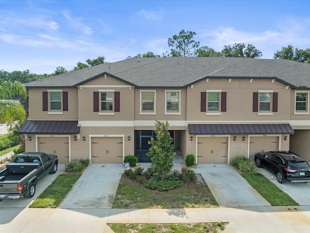 townhome / multi-family property featuring driveway, a standing seam roof, and metal roof