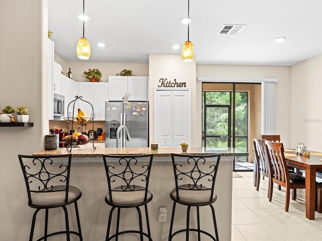 kitchen featuring appliances with stainless steel finishes, decorative light fixtures, white cabinets, and dark stone countertops