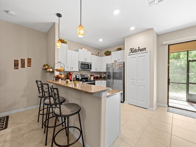 kitchen featuring stainless steel appliances, white cabinets, kitchen peninsula, light tile patterned flooring, and dark stone countertops