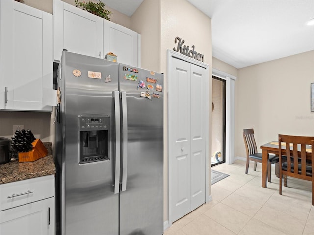 kitchen featuring light tile patterned floors, stainless steel refrigerator with ice dispenser, dark stone countertops, and white cabinets