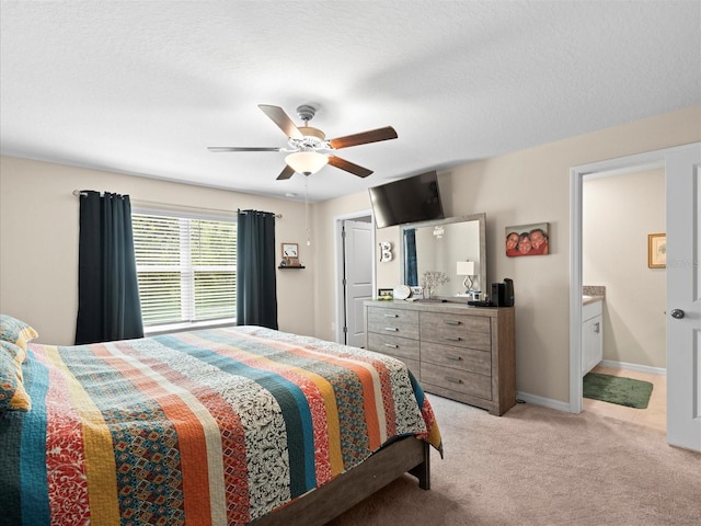 carpeted bedroom featuring ceiling fan, a textured ceiling, and ensuite bath