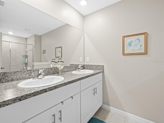 bathroom with double sink vanity, a tile shower, and tile patterned floors