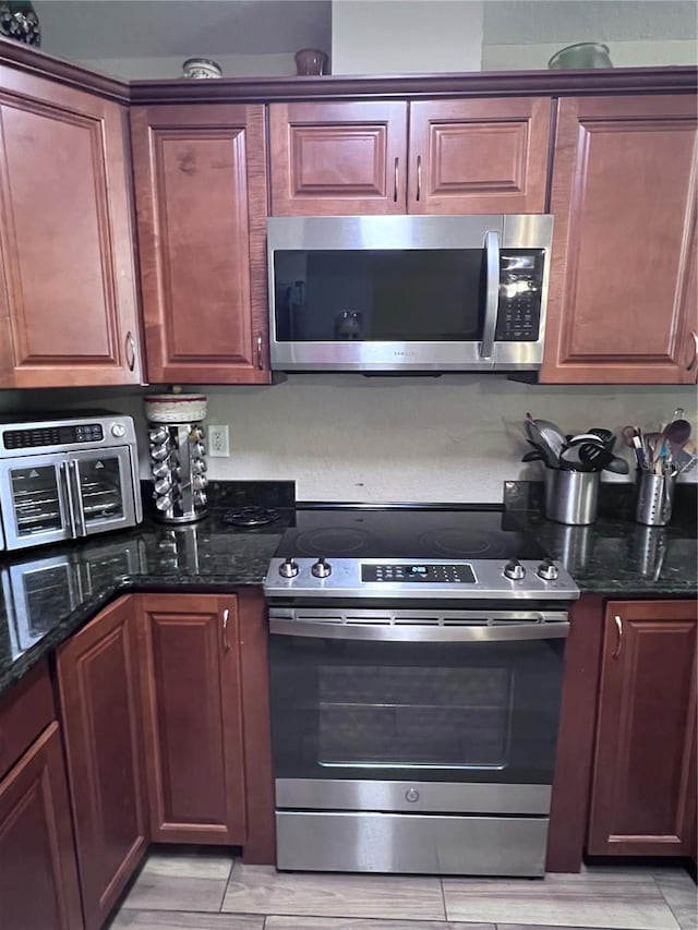 kitchen featuring appliances with stainless steel finishes and dark stone countertops