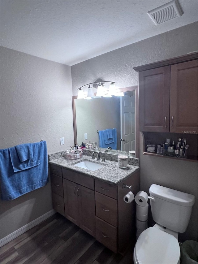 bathroom with hardwood / wood-style flooring, vanity, and toilet