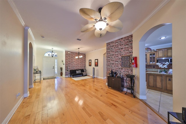 living area with arched walkways, ornamental molding, and light wood-style flooring