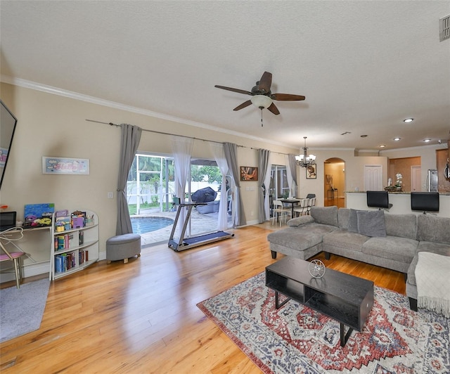 living room featuring arched walkways, visible vents, crown molding, and wood finished floors