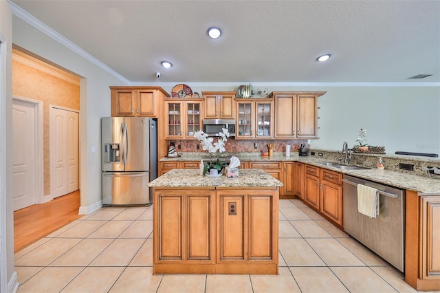 kitchen with light tile patterned flooring, stainless steel appliances, a sink, light stone countertops, and brown cabinetry