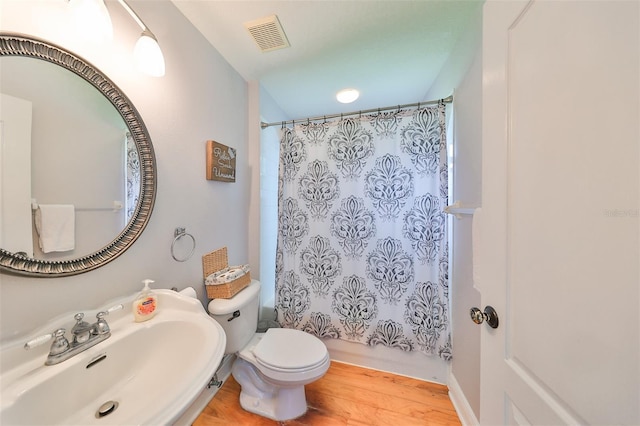 bathroom featuring shower / tub combo with curtain, visible vents, toilet, a sink, and wood finished floors