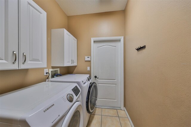 laundry area featuring a textured ceiling, cabinets, washer and clothes dryer, and light tile patterned floors