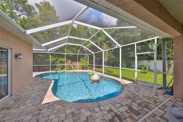 outdoor pool with glass enclosure, fence, a lawn, and a patio