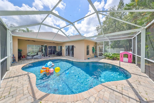 view of pool with glass enclosure, ceiling fan, and a patio area