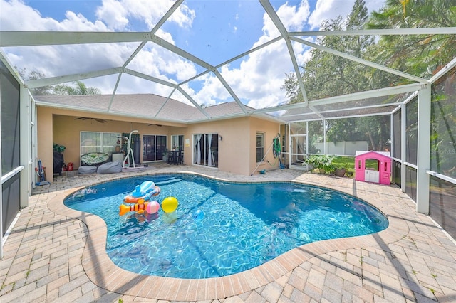 pool featuring a ceiling fan, glass enclosure, and a patio area