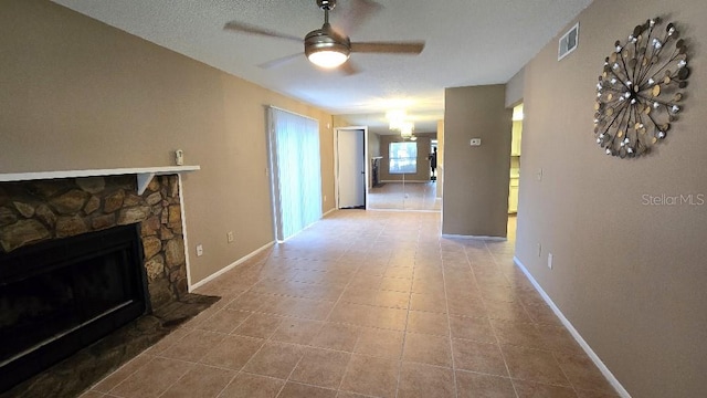 living room featuring ceiling fan, a stone fireplace, and tile patterned floors