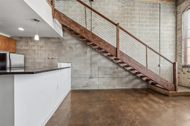 interior space featuring stainless steel fridge and pendant lighting