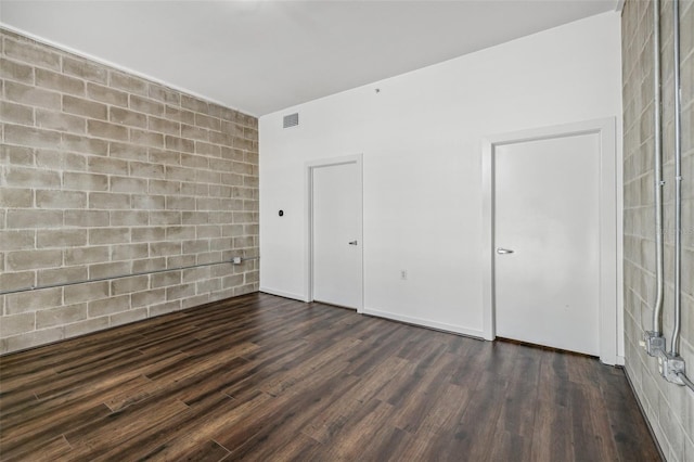 spare room featuring hardwood / wood-style floors and brick wall