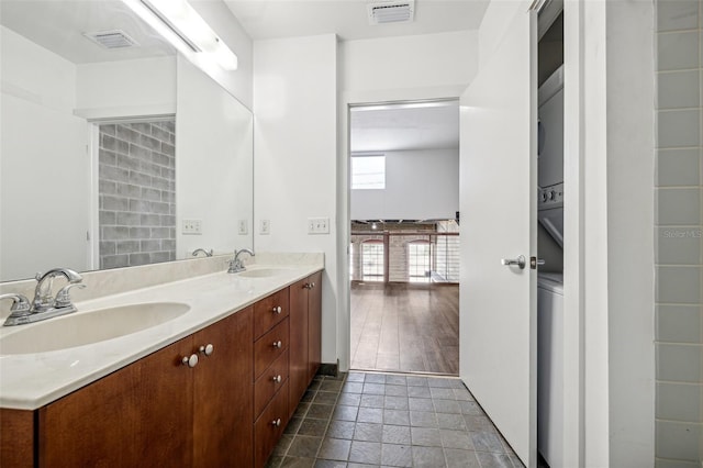 full bathroom featuring stone tile flooring, visible vents, a sink, and double vanity