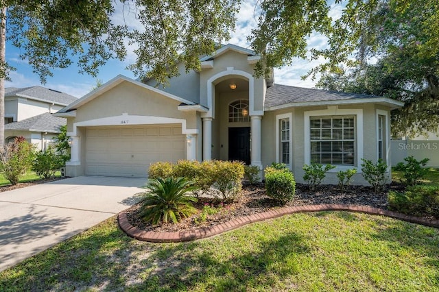 view of front of house with an attached garage, driveway, a shingled roof, and stucco siding