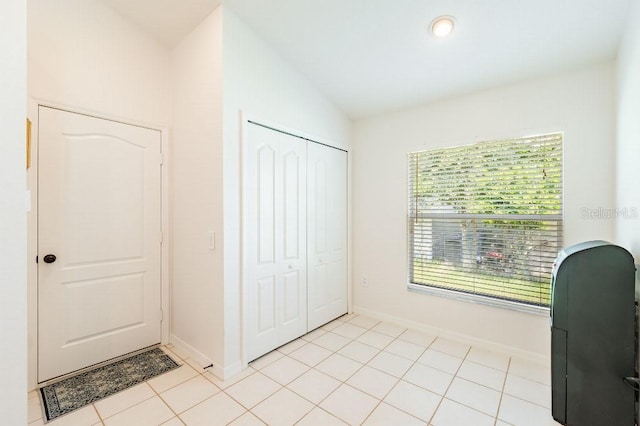 unfurnished office featuring lofted ceiling, light tile patterned flooring, and baseboards